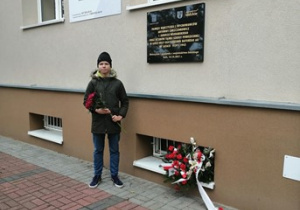 Uczeń klasy 8b składa kwiaty przy tablicy upamiętniającej łódzkich bohaterów walczących o polską szkołę.